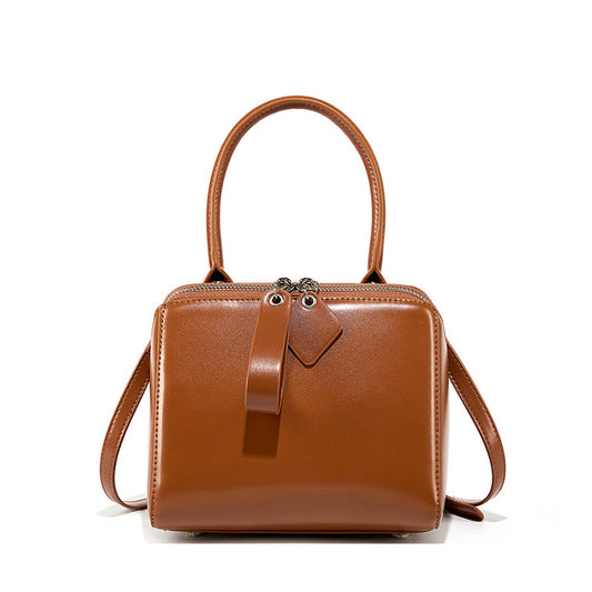 Brown leather handbag with a strap on a white background