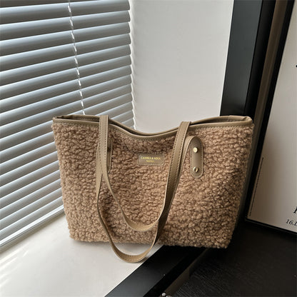 Beige textured handbag on a surface with blinds in the background