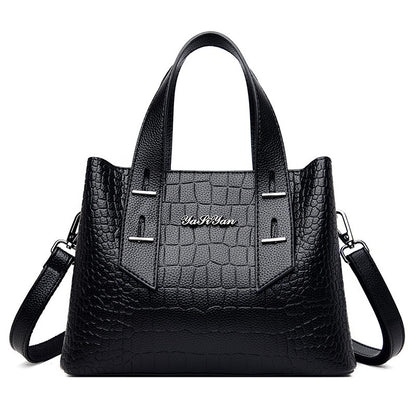 Black handbag with crocodile texture and visible brand name on a white background