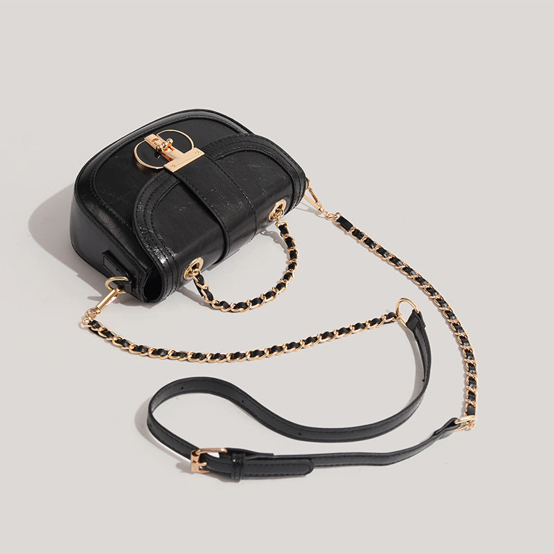 Black handbag with gold chain strap on a light gray background