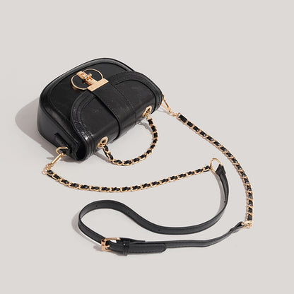 Black handbag with gold chain strap on a light gray background