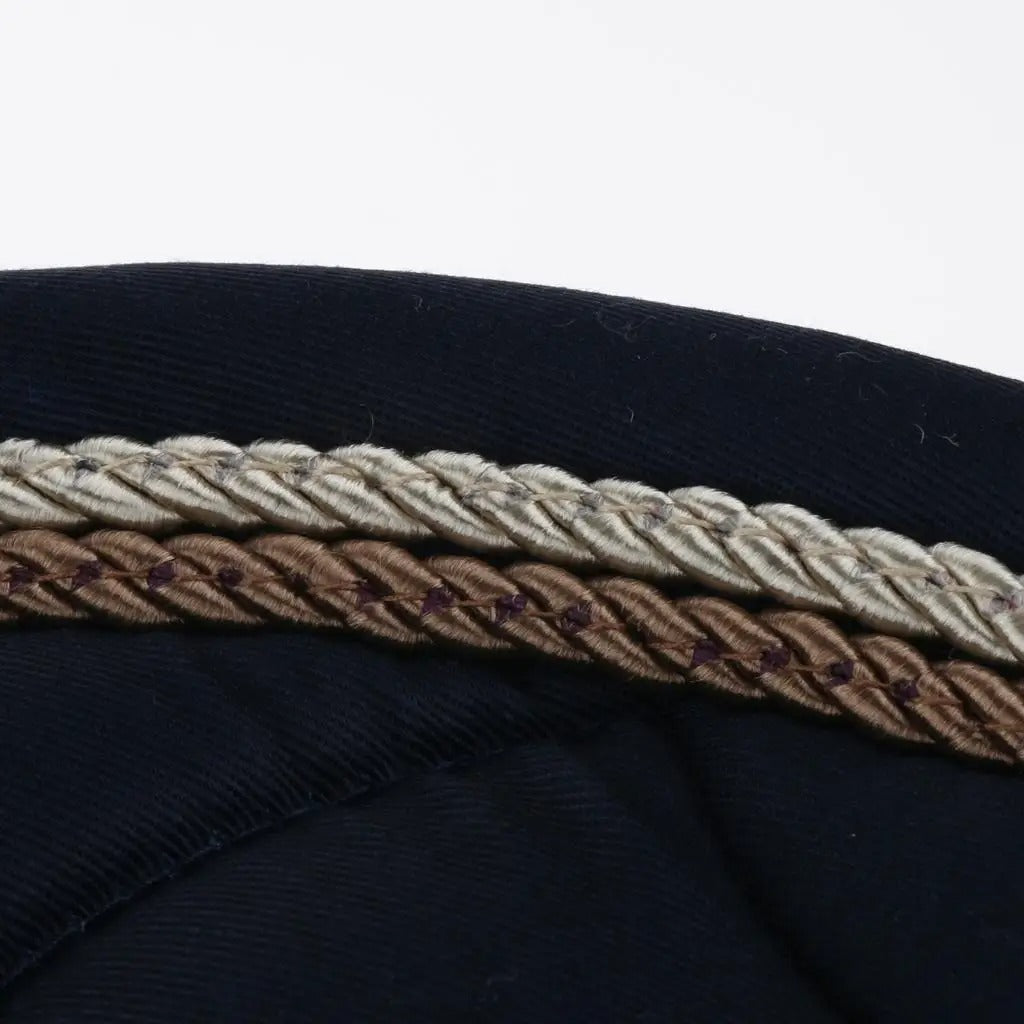 Close-up of a navy blue fabric with a braided trim featuring brown, beige, and white colors.