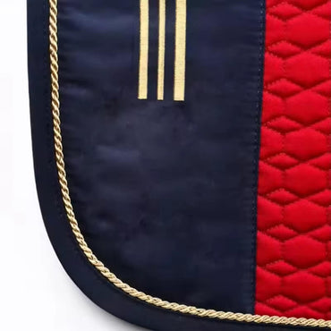 Close-up of a saddle pad with navy, red, and gold colors on a white background