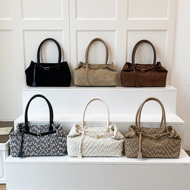 Collection of handbags displayed on a white surface against a white paneled wall.