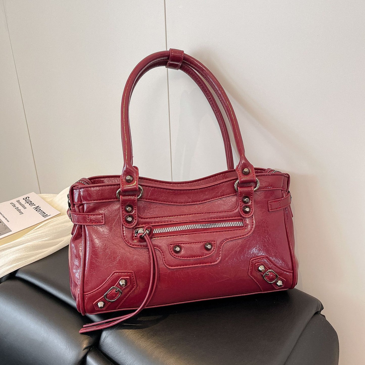 Red handbag on a black chair with a white wall background