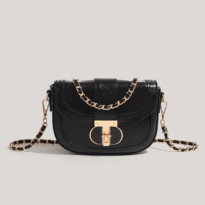 Black handbag with gold chain strap on a light gray background