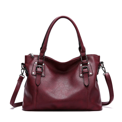 Maroon handbag with silver buckles on a white background