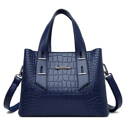 Blue handbag with crocodile texture and visible brand name on a white background