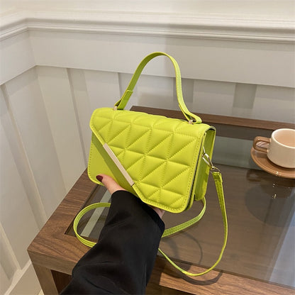 Person holding a bright green quilted handbag on a wooden surface with a blurred background
