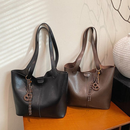 Two leather handbags, one black and one brown, on a wooden surface with a neutral background.